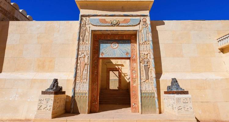 Puerta histórica de temática egipcia con jeroglíficos y estatuas.