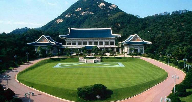 Un grand palais entouré d'une verdure luxuriante et d'une montagne en arrière-plan.
