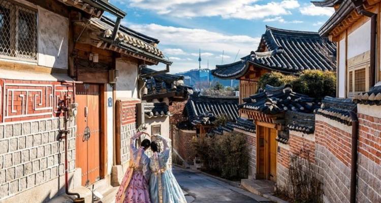 Deux personnes en tenue traditionnelle marchant dans une rue coréenne historique.