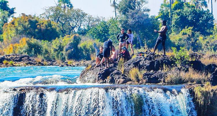 Des gens se rassemblent près du bord d'une petite cascade.