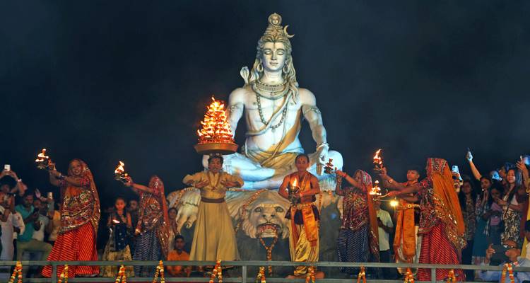 Groupe de personnes effectuant une cérémonie traditionnelle devant une grande statue.