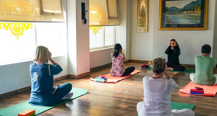 Groupe pratiquant le yoga à l'intérieur dans une pièce très éclairée.