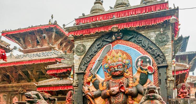 Stenen sculptuur van een godin in een levendige tempelomgeving in Kathmandu.