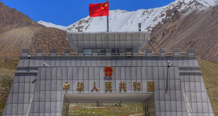 Porte frontière du col de Khunjerab avec drapeau chinois sur fond de pics enneigés du Karakoram.