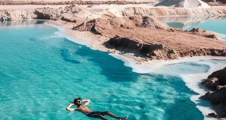 Personne flottant sur une eau turquoise dans une oasis du désert.