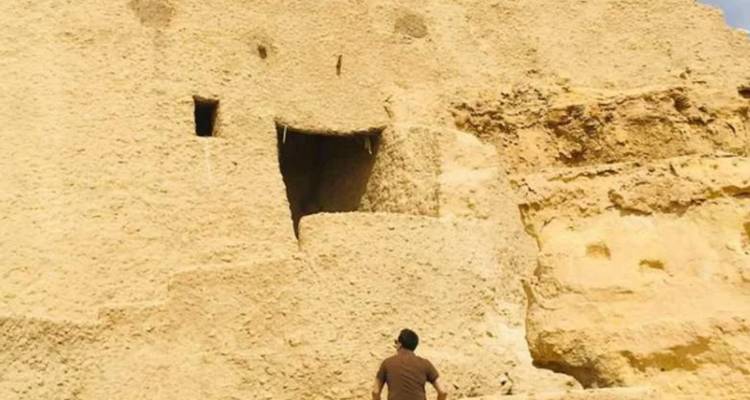 Personne explorant une grande structure de pierre dans un désert.