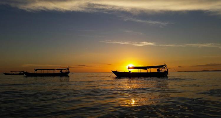 Siluetas de barcos en el agua al atardecer.