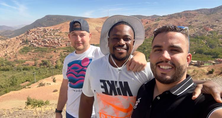 Trois hommes posant avec un paysage rural en arrière-plan.