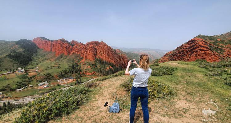 A person taking a photo of a rugged cliff landscape.