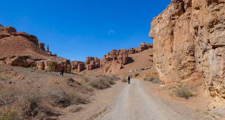 Des visiteurs marchant à travers un canyon avec d'imposantes formations rocheuses.