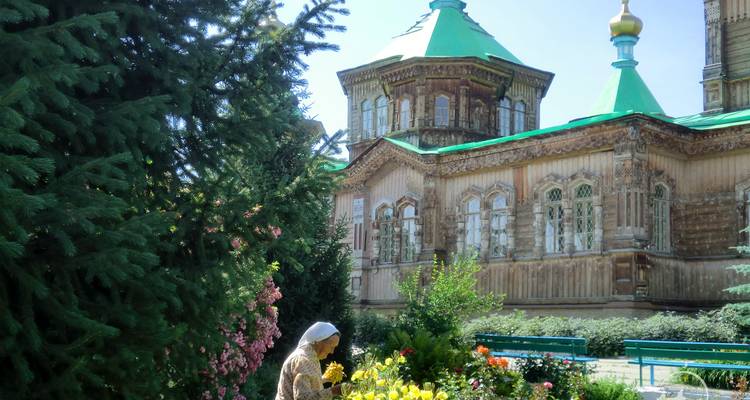 Woman admiring a wooden church and gardens.
