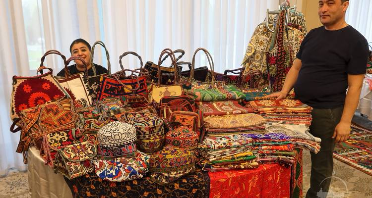 Des gens vendant des textiles traditionnels colorés à un étal de marché.