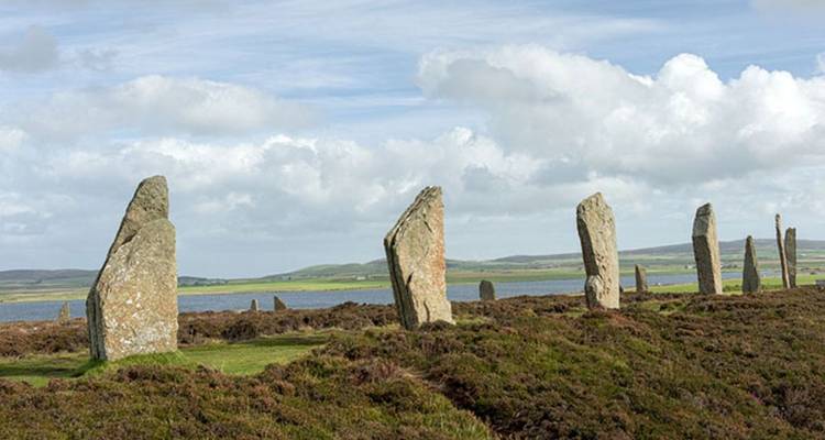 Anciennes pierres dressées d'un cercle préhistorique formant une ligne sur une lande ouverte et le ciel.