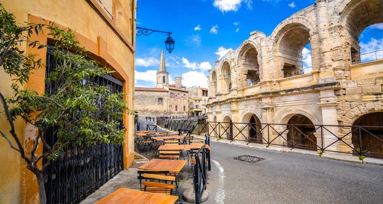 Café situé à côté d'un amphithéâtre antique et d'une rue pavée.