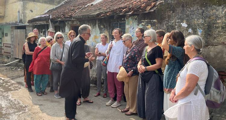 Gruppe von Touristen, die einem Führer in einem historischen Dorf zuhören.