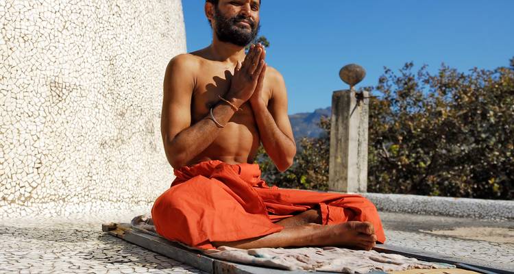 Mann, der auf einem Dach mit malerischer Kulisse meditiert.
