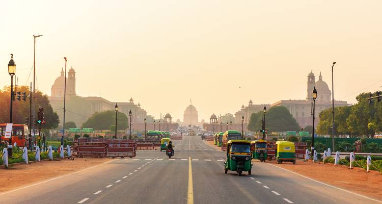 Straße, die zu historischen Gebäuden führt, mit vorbeifahrenden Tuk-Tuks.