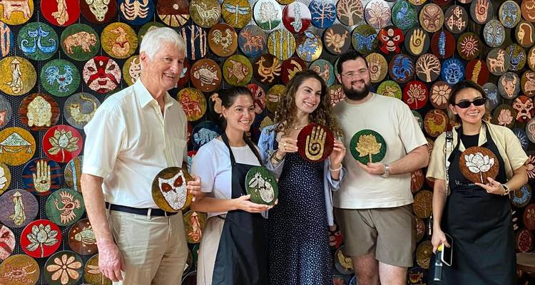 Groupe tenant des éventails décorés souriant dans un atelier.