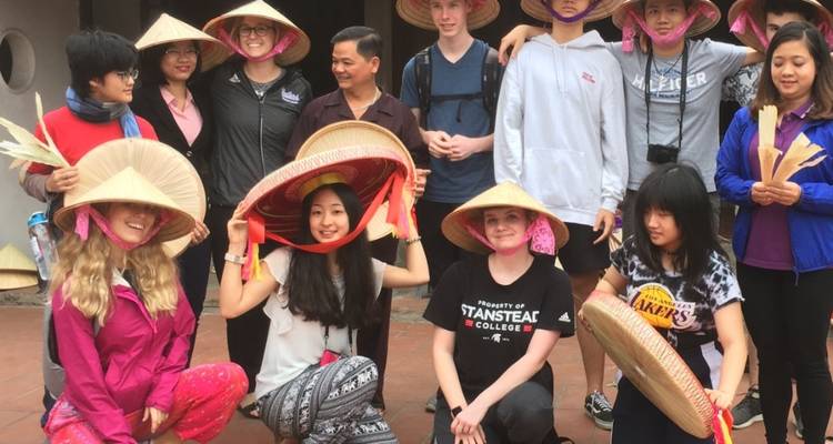 Groupe de touristes portant des chapeaux traditionnels, posant pour une photo.