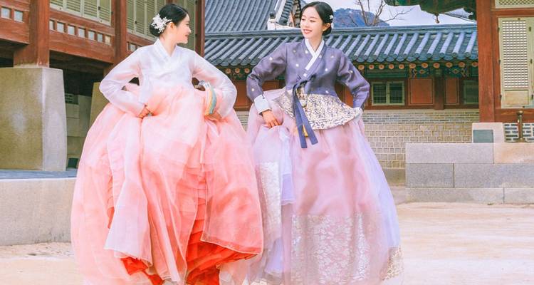 Deux femmes en robes coréennes traditionnelles dans une cour.