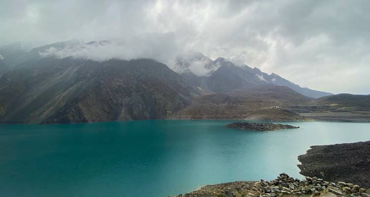 Lac turquoise mélancolique sous des montagnes déchiquetées voilées de brume.