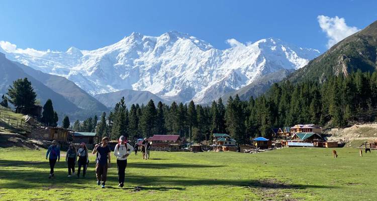 Los excursionistas pasean por las verdes Praderas de las Hadas con imponentes picos nevados de fondo