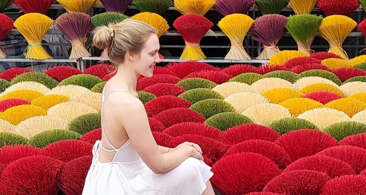 Femme en blanc assise dans un champ coloré de plantes arrangées.