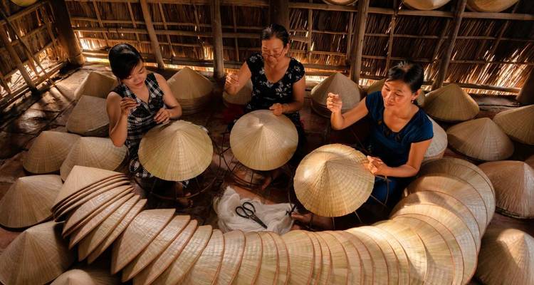 Femmes confectionnant des chapeaux traditionnels à l'intérieur d'une hutte.