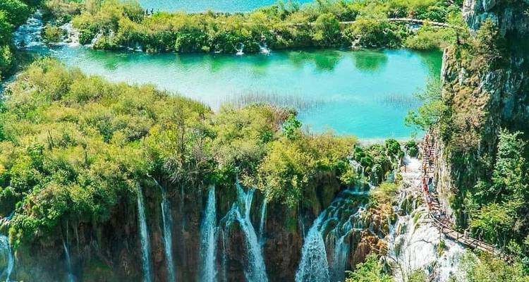 Lush green landscape with waterfalls and lakes.