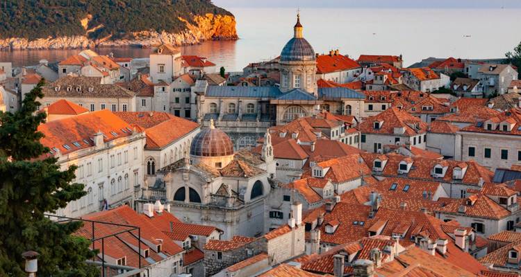 Historic cityscape view with orange rooftops and a cathedral.