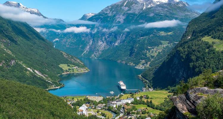 Uitzicht op een fjord omringd door bergen, met een cruiseschip zichtbaar.