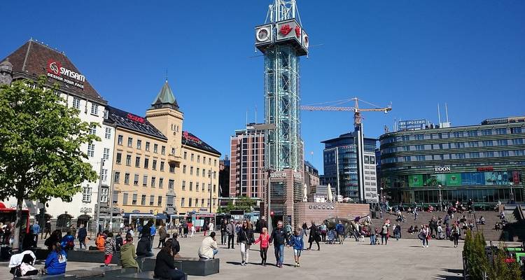 Open openbaar plein met een klokkentoren, mensen lopen rond.
