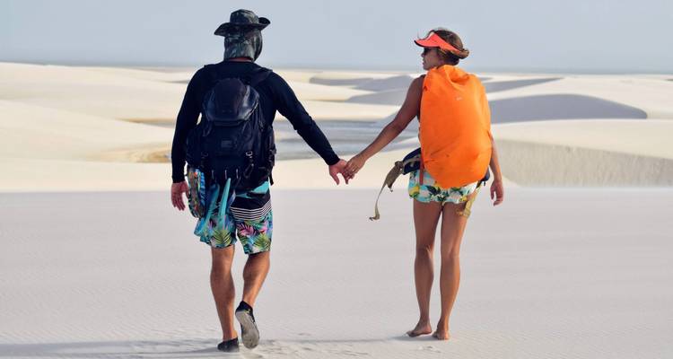 Couple marchant main dans la main à travers les dunes de sable.