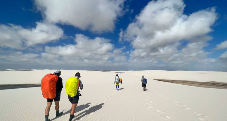 Groupe faisant du trekking à travers les dunes de sable avec des sacs à dos.