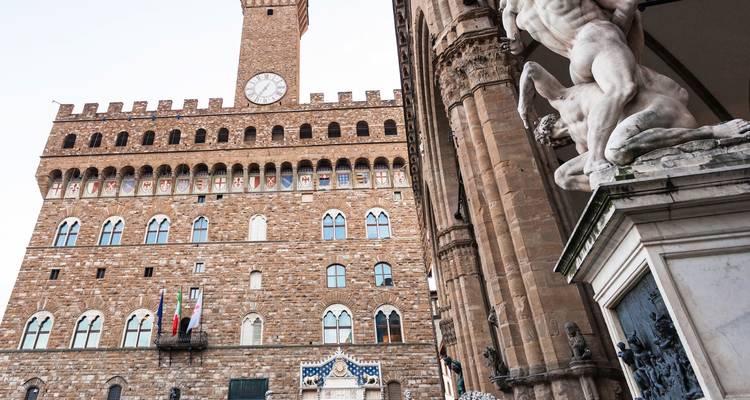 Bâtiment historique avec une tour d'horloge et des statues.