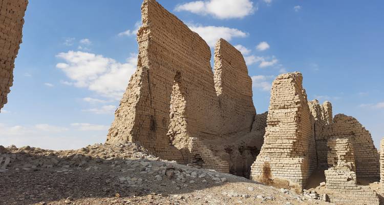 Murs anciens en ruines avec un ciel partiellement nuageux en arrière-plan.