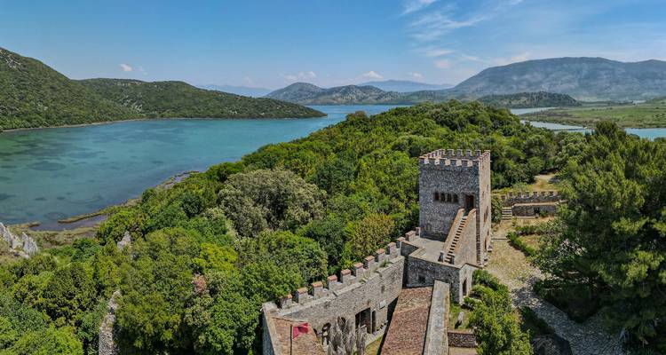 Une structure semblable à un château avec des tours entourée d'une végétation luxuriante et d'un plan d'eau.