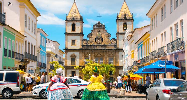 Colorful colonial street scene with historic church and people in traditional attire.