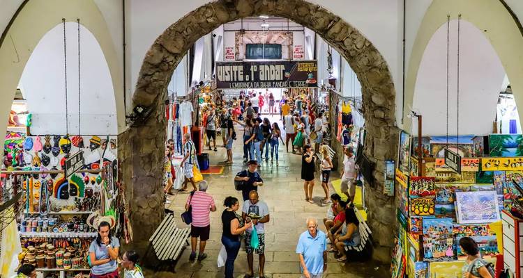 Bustling market with various shops under arched entryway.