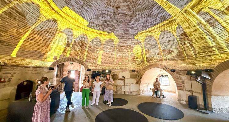 Personas dentro de un edificio abovedado con arcos de ladrillo y exhibiciones interactivas.