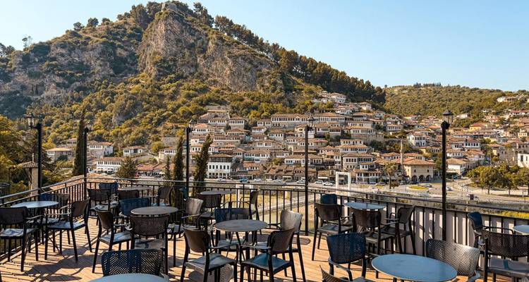 Con vista a una terraza con mesas vacías y una vista de casas en la ladera.