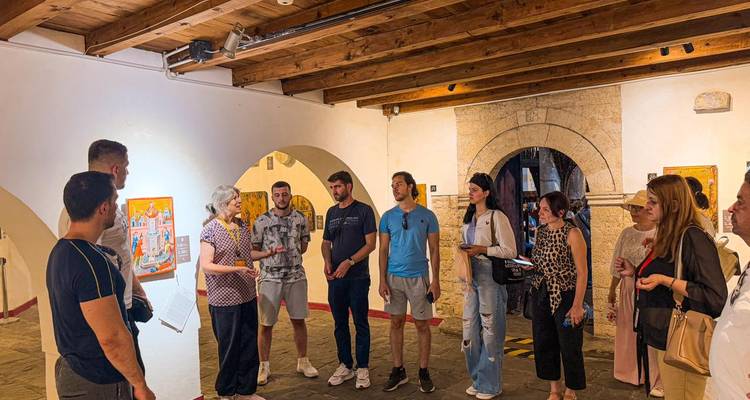 Grupo de turistas escuchando a un guía dentro de una galería con arcos.