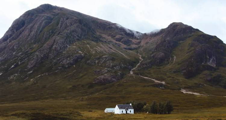 Une chaumière pittoresque devant une grande montagne.