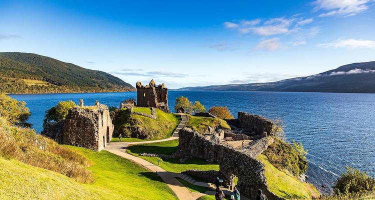 Ruines sur une colline surplombant un grand lac.