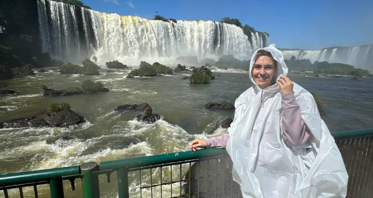 Person in a rain poncho in front of large waterfalls.