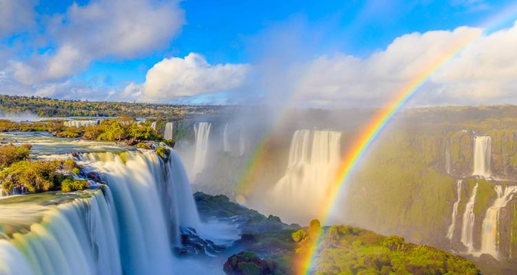 Massive waterfalls with visible rainbows in a natural setting.