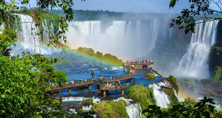 Tourists on a viewing platform overlooking powerful waterfalls.