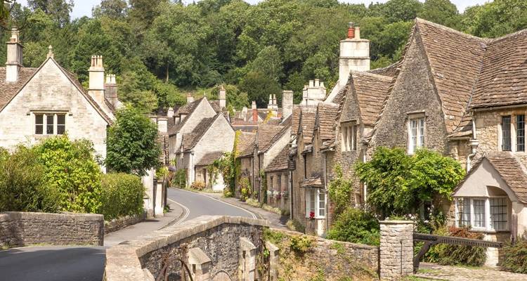 Village pittoresque avec cottages en pierre et toits de tuiles sur une route sinueuse.