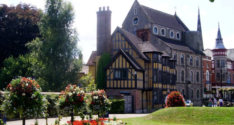 Bâtiment historique à colombages situé dans un jardin paysager.