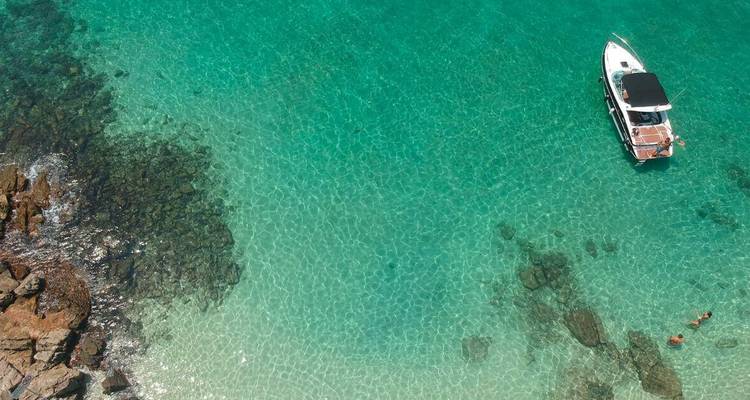 Vue aérienne d'un petit bateau dans une eau cristalline.
